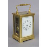 A large carriage clock in gilt brass case, with black roman numerals to the white enamel dial, the
