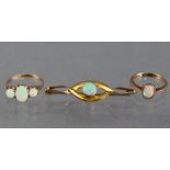 An opal ring set oval stone flanked by a smaller round-cut stone either side, to an un-marked yellow