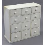 A white painted small chest, fitted three ranks of four short drawers with turned knob handles, & on