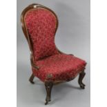 A late 19th century carved beech frame spoon-back nursing chair, with padded seat & back upholstered