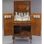 A 1970’s carved walnut cocktail cabinet, with fitted interior enclosed by hinged lift-lid & pair