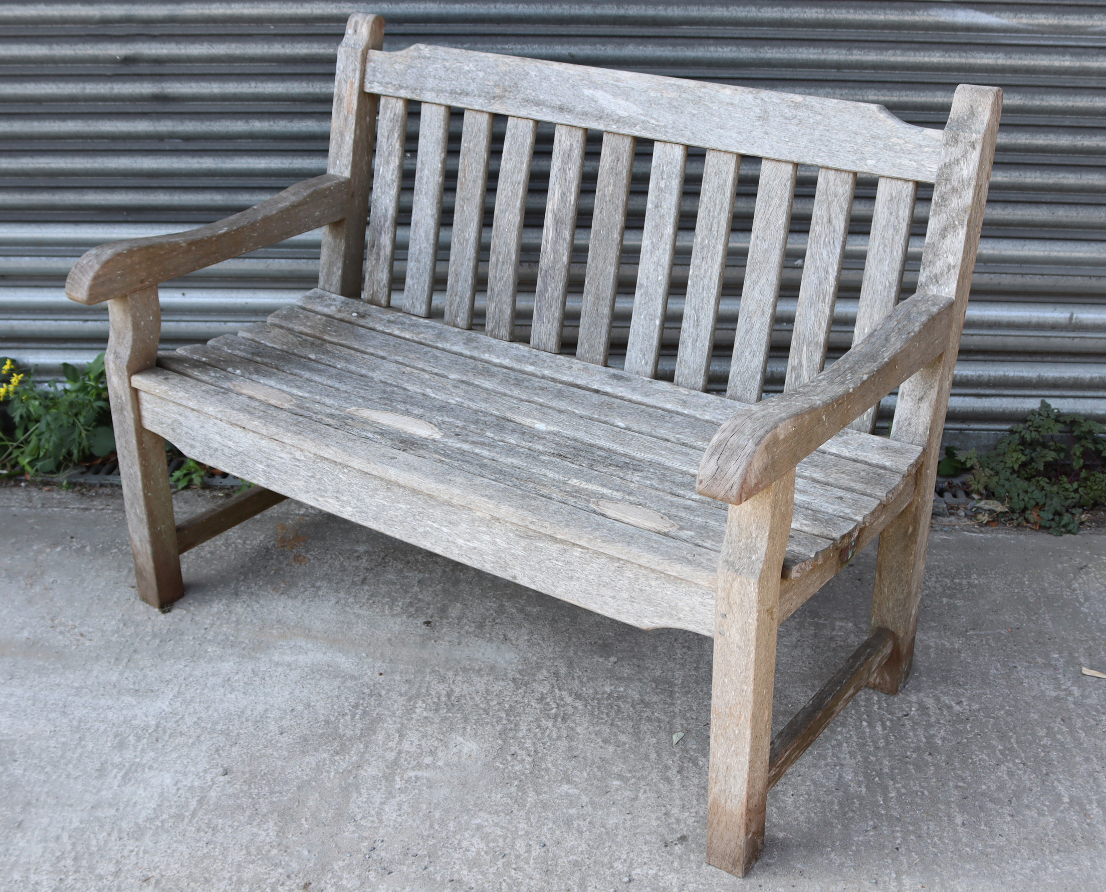 A teak slatted garden bench, on square legs with plain stretchers, 48” long.