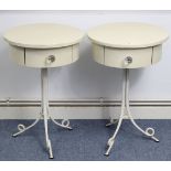 A pair of cream finish bedside tables, each with circular top, fitted frieze drawer, & on white