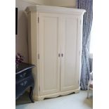 A Laura Ashley continental-style white painted pine wardrobe with moulded cornice, enclosed by pair