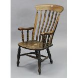 A Victorian lath-back elbow chair with hard seat, & on turned legs with spindle stretcher.