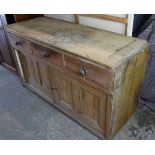 A pine dresser base, fitted three frieze drawers above cupboard enclosed by pair of sliding panel