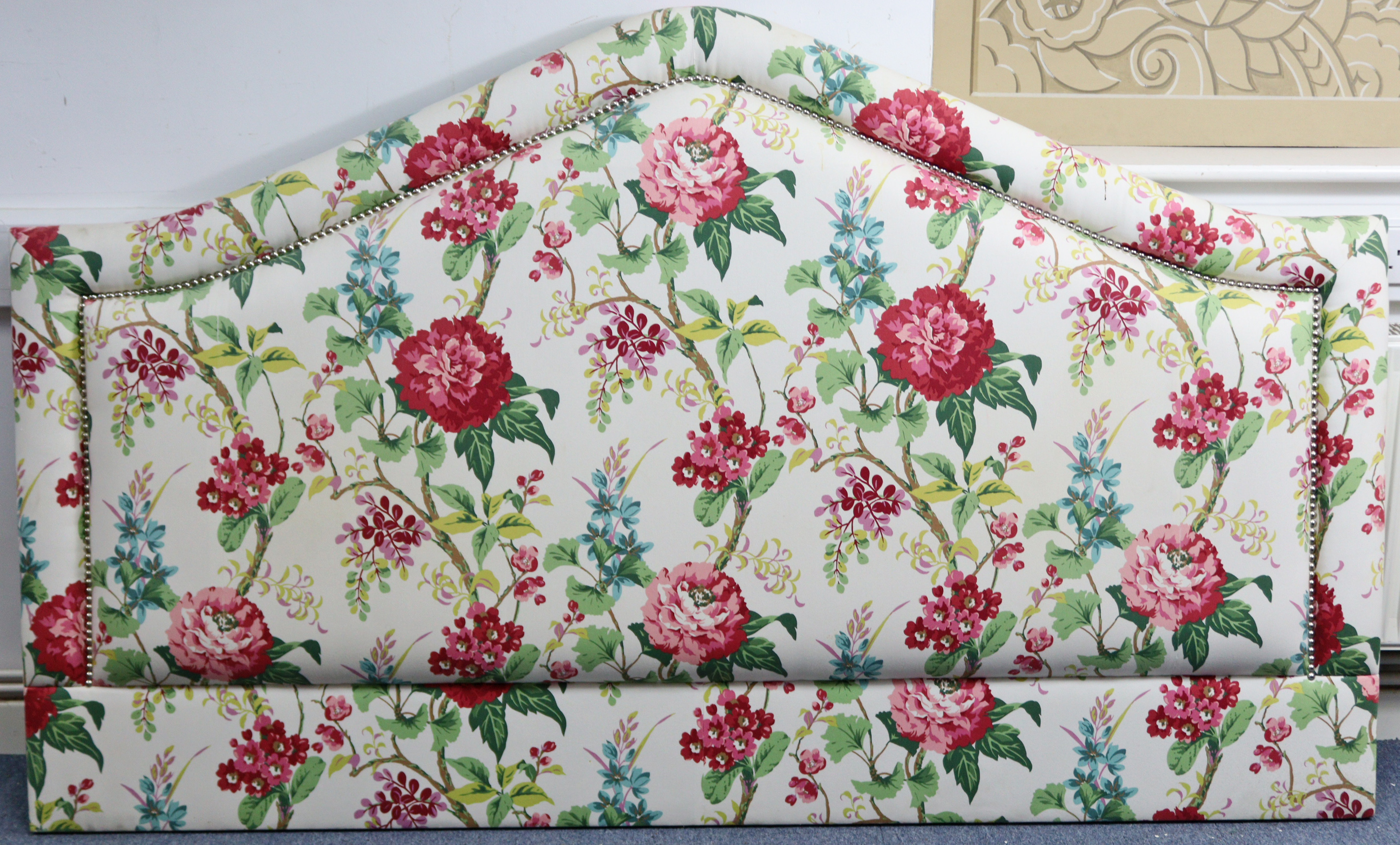 A large padded headboard, upholstered multi-coloured floral material, 79” long x 47½” high.