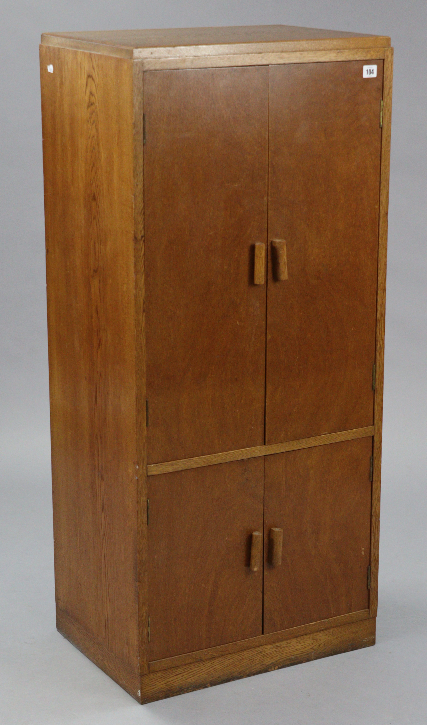 A mid-20th century oak upright cupboard, enclosed by two pairs of panel doors, & on plinth base, 22”
