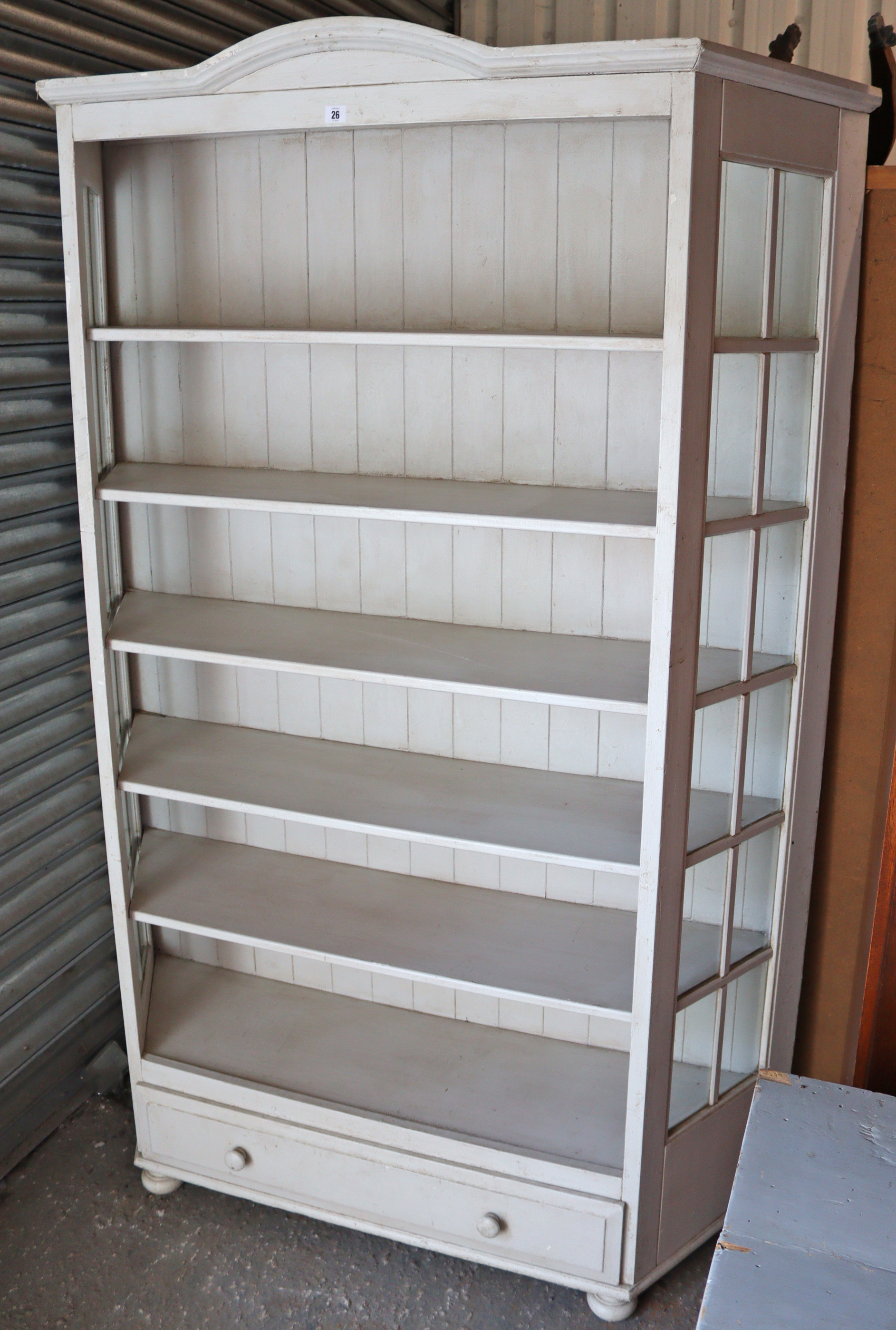 A light grey painted pine tall standing open bookcase, fitted five shelves above a long drawer, with