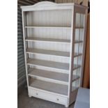 A light grey painted pine tall standing open bookcase, fitted five shelves above a long drawer, with