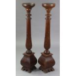 A pair of hardwood torcheres with carved & turned centre columns, & on shaped plinths, 9” diam. x