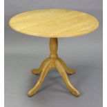 A light oak pedestal dining table with circular top, & on vase-turned centre column & four splay