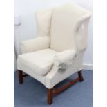 A Georgian-style wing-back armchair upholstered cream material, & on short moulded square legs.