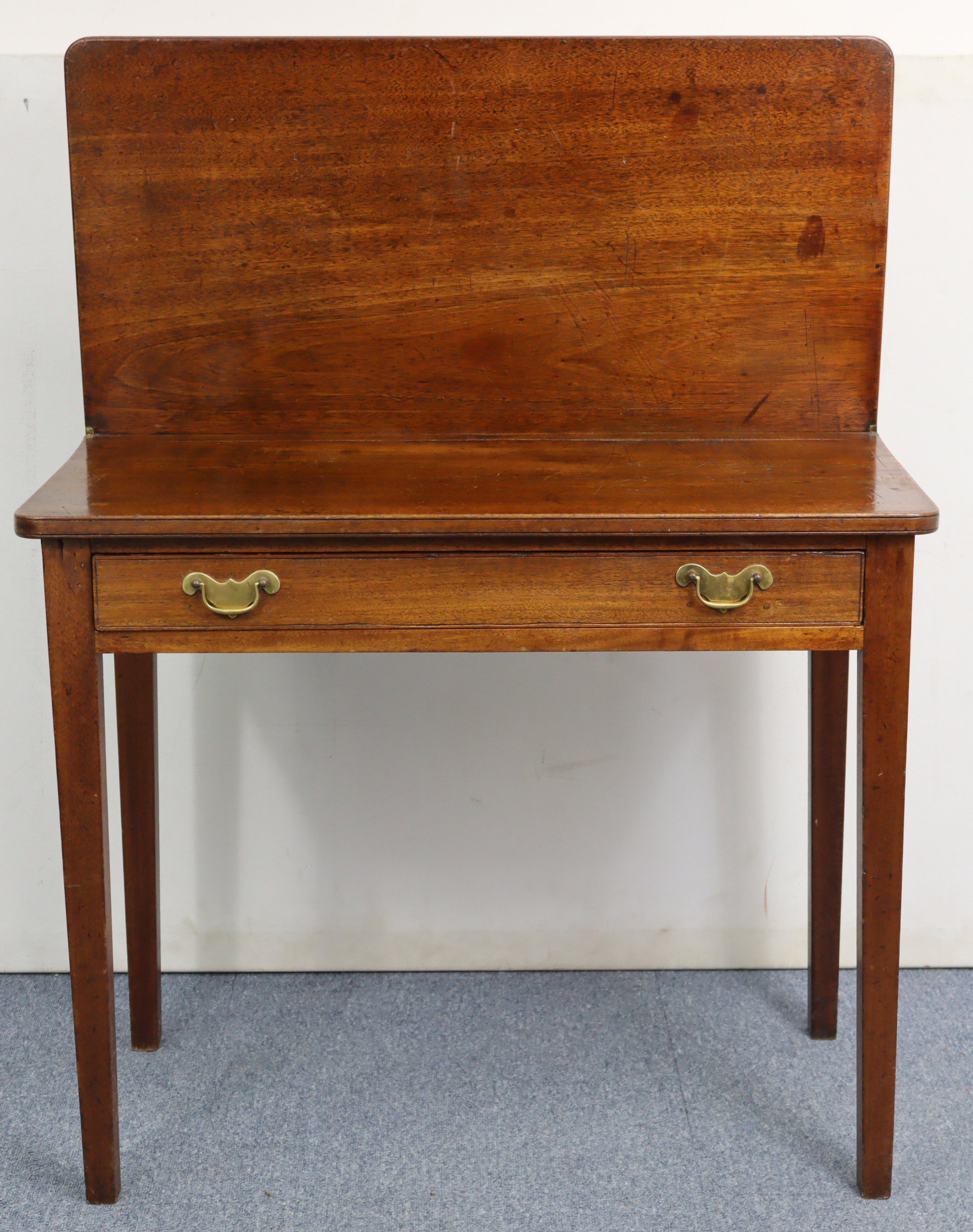 A 19th century mahogany tea table with rectangular fold-over top, fitted frieze drawer & on square