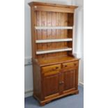 A pine small dresser, the upper part fitted three open shelves & with panelled back, the base fitted