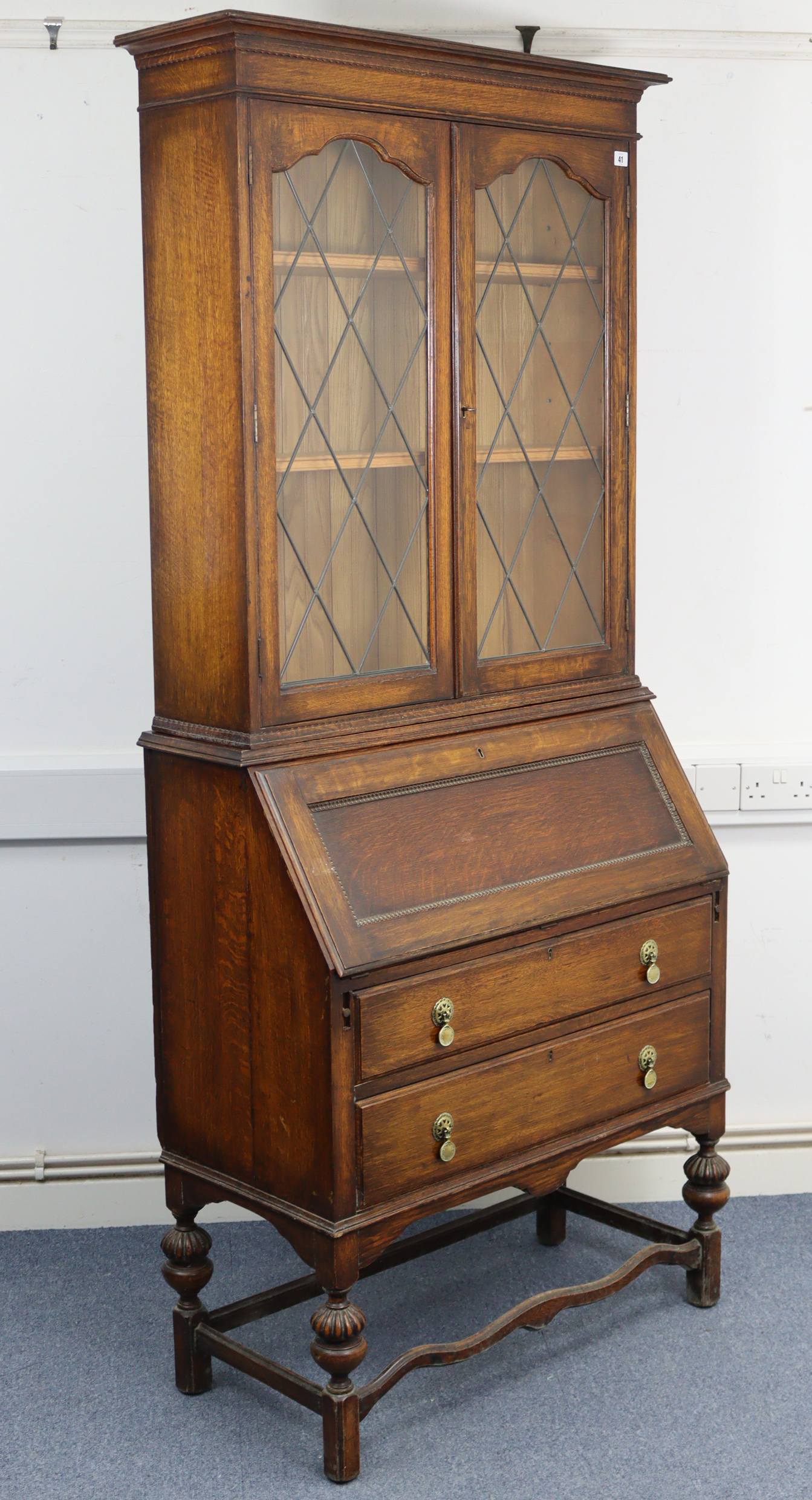 A 1930’s oak bureau-bookcase, the upper part with two adjustable shelves enclosed by pair of