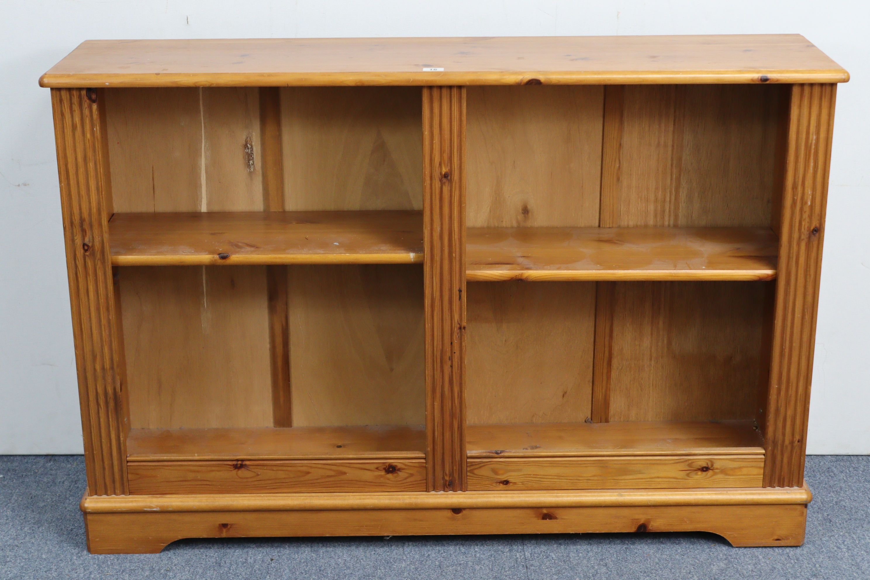 A pine low standing open bookcase with two adjustable shelves, & on shaped plinth base, 47” wide x