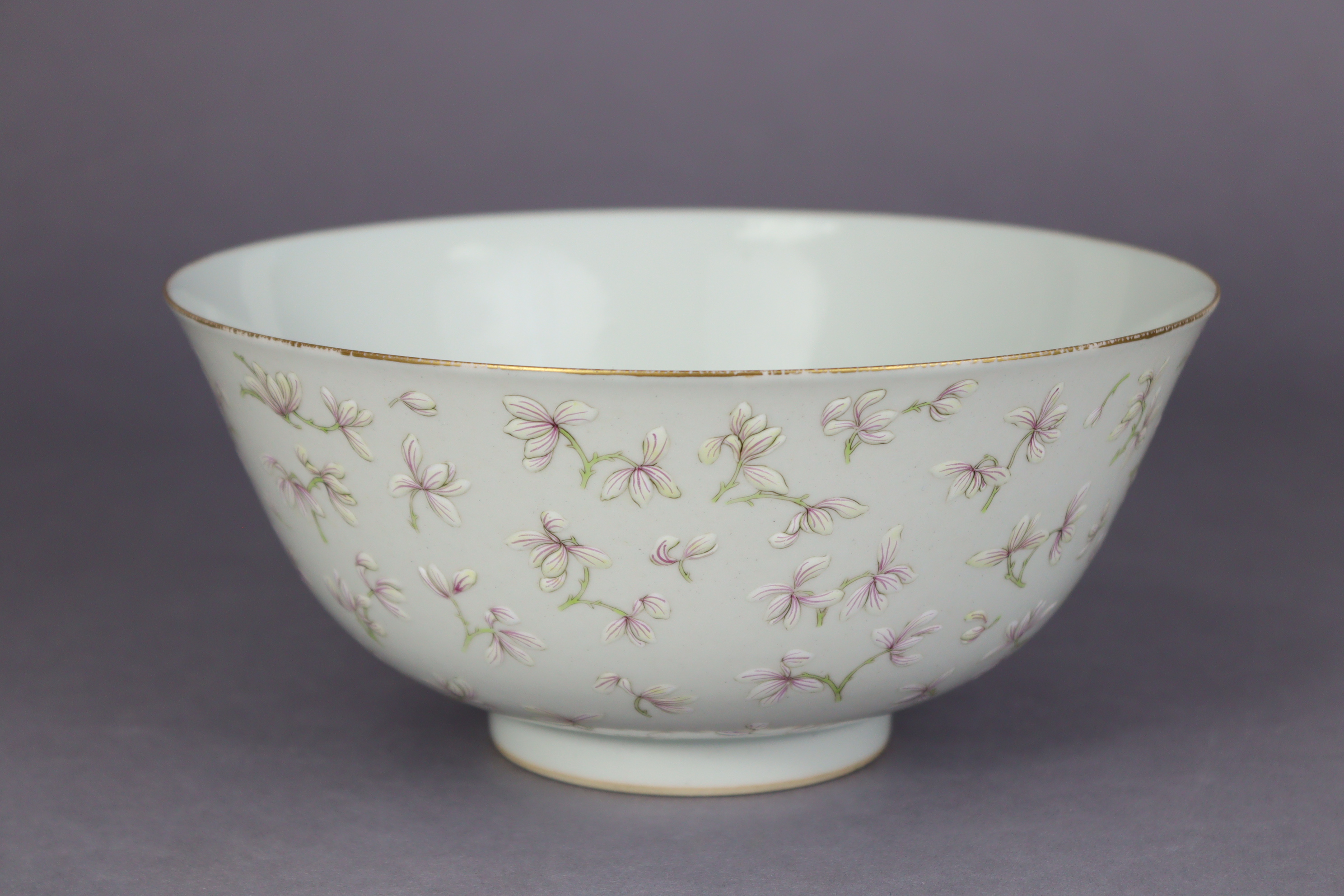 A Chinese porcelain bowl of off-white ground, the exterior with all-over decoration of blossoming