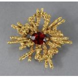 A 9ct. gold brooch of abstract form, set oval garnet to the centre, 1¼” wide over-all. (8gm).