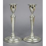 A pair of George V silver candlesticks in the late 18th century style, with vase-shaped nozzles,