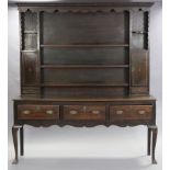 A George III inlaid oak dresser, with moulded dentil cornice above an arrangement of five shelves