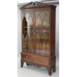 A George III inlaid-mahogany standing bookcase, with broken-arch pediment & urn finial above four