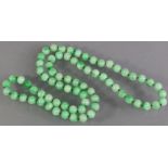 A JADE NECKLACE of seventy-three spherical beads of uniform size & mottled green/white colour,