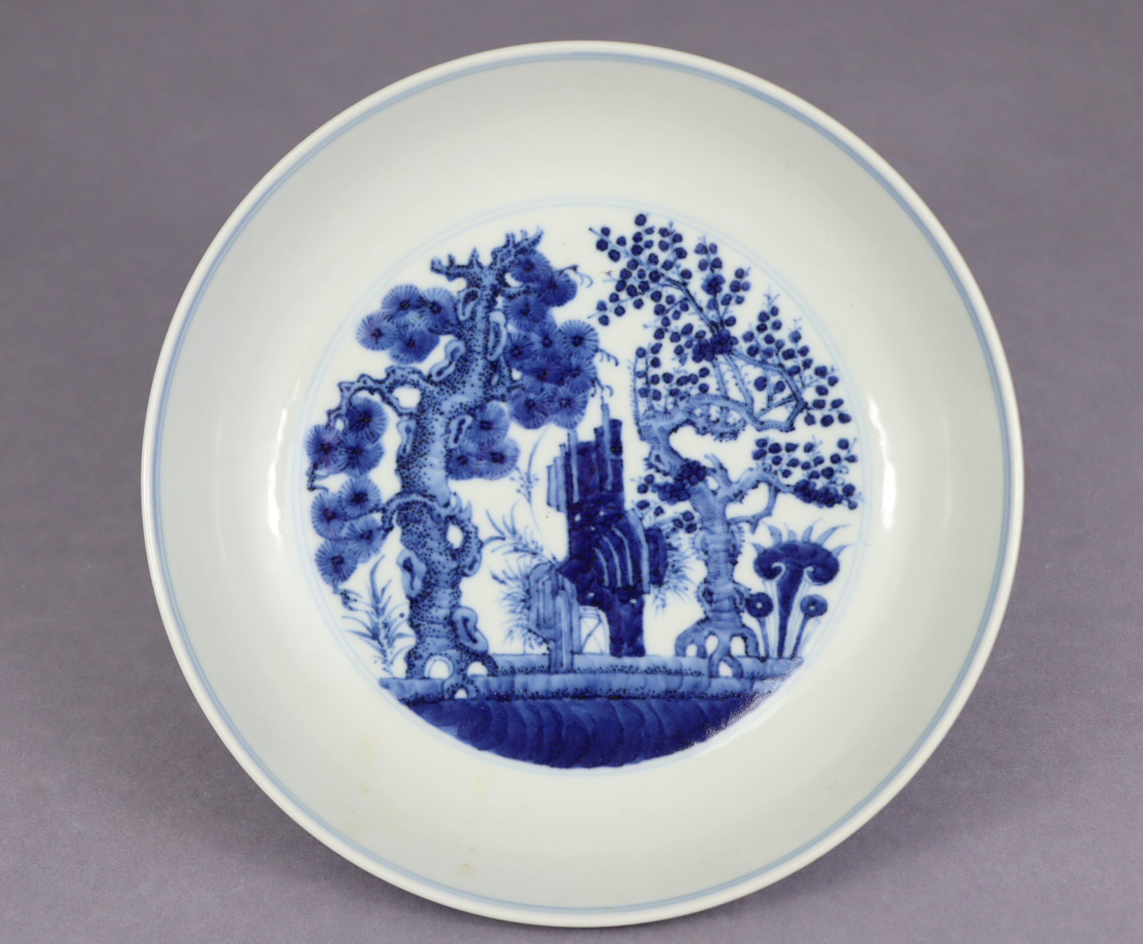 A Chinese blue & white porcelain shallow bowl, the centre decorated with pine, lingzhi, & prunus