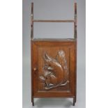 A late Victorian oak hanging wall cabinet, enclosed by fielded panel door with relief-carved