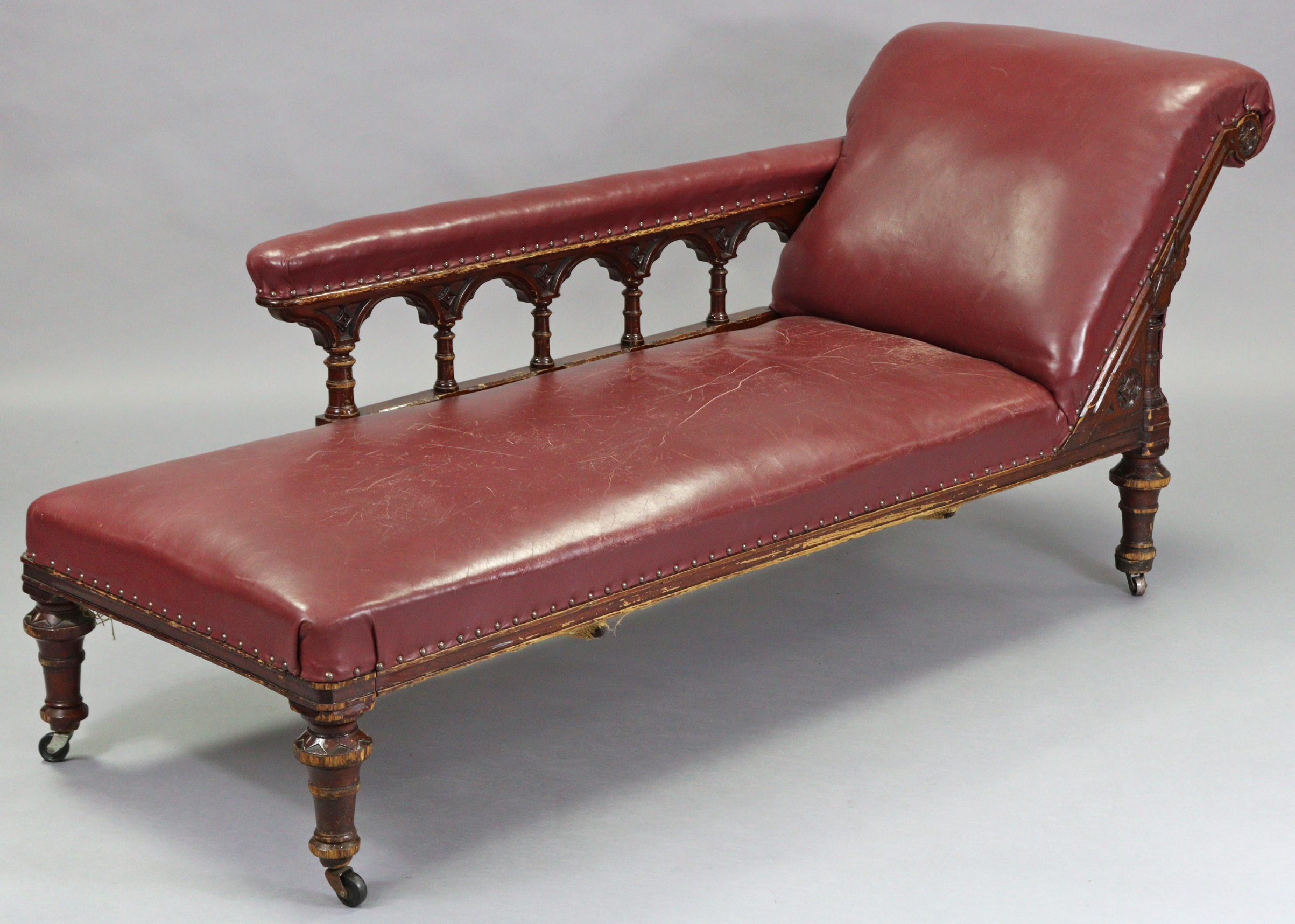 A Victorian carved oak frame chaise longue upholstered brass-studded crimson leather, with foliate