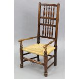 A 19th century Lancashire-type ash elbow chair with spindle-rail back, rush seat, & on turned legs