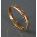 A 9ct. gold stiff hinged bangle with engraved decoration to one half; Chester hallmarks for 1912. (