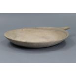 An antique carved stone large shallow settling pan, with handle to one end; 23½” diam. x 29” wide.