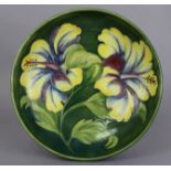 A Moorcroft pottery large shallow bowl decorated in the “Hibiscus” design, on a green ground.