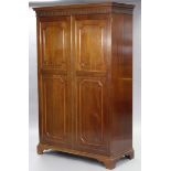 A mahogany wardrobe, with moulded dentil cornice above hanging compartment with brass rail, enclosed