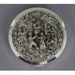A continental white metal powder compact, the circular hinged lid embossed with dancing figures in