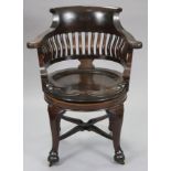 A late 19th century mahogany revovling desk elbow chair with curved rail supports to the rounded ba