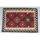 A Maiman kilim rug with central repeating geometric design in red, orange, yellow, green, & blue