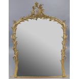 A 19th century arched overmantel mirror in foliate carved giltwood frame with scrolling surmount;