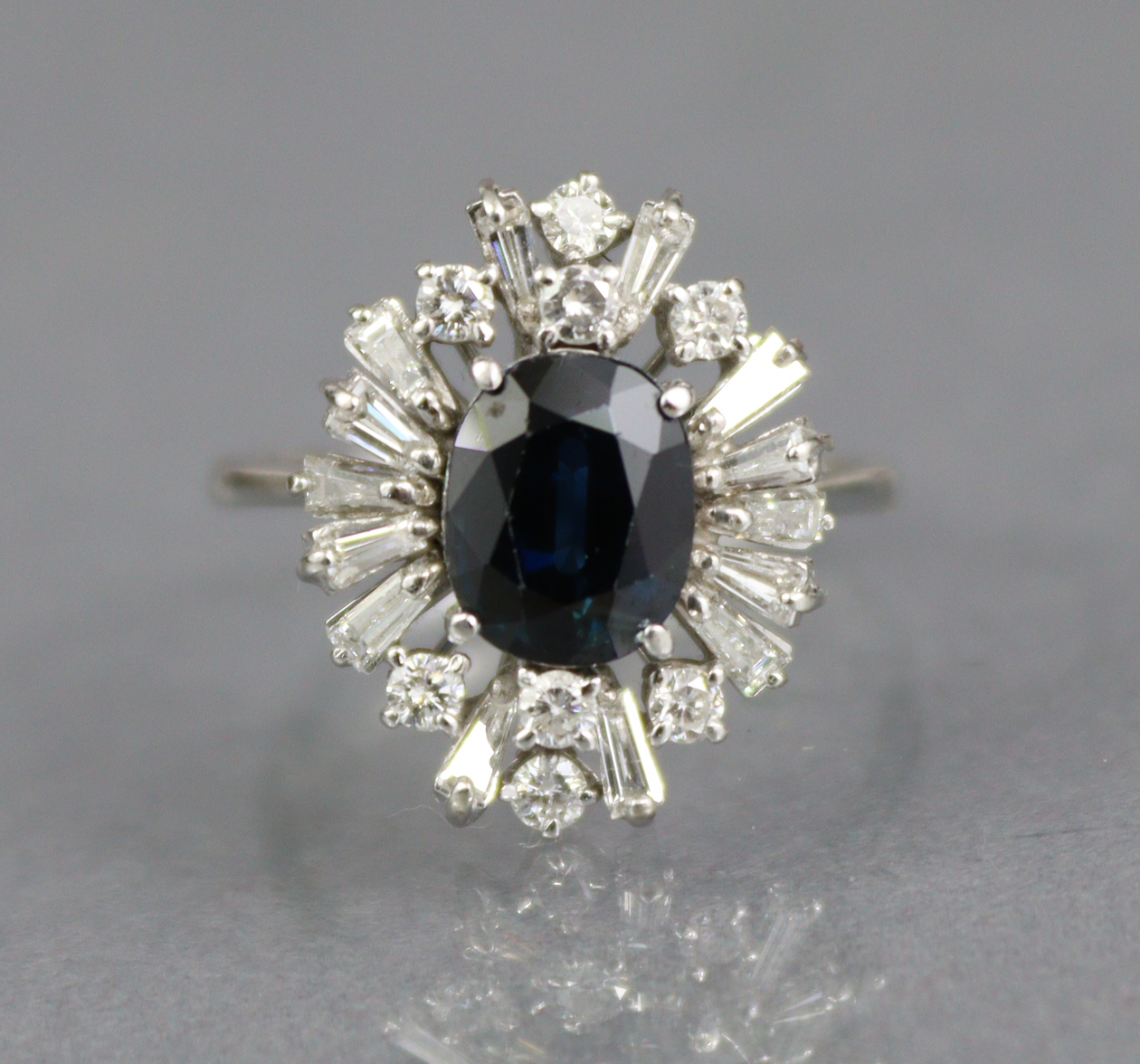 A SAPPHIRE & DIAMOND RING, the oval-cut sapphire approx. 2 carats set within a radiating border of