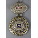 An Indian white metal large circular flat-sided pendant inset lapis to the centre within a border of