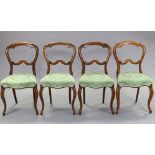 A set of four mid-Victorian balloon-back dining chairs with foliate carved centre rails, padded