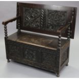 A late Victorian carved oak monk’s bench, with stylised foliate decoration to the three-panel
