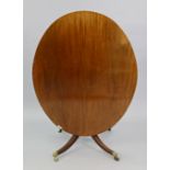 A regency mahogany oval tilt-top dining table, with plain edge & original brass catch, on turned