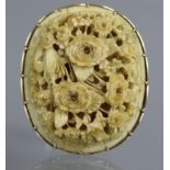 A Chinese carved & pierced ivory oval brooch in the form of a floral spray, with 9ct. gold mount; 2”