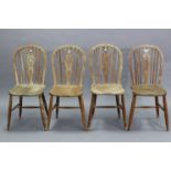 A set of four pine wheel-back kitchen chairs with hard seats, & on turned legs with spindle