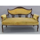 An Edwardian beech-frame three-seater settee with padded seat, back, & arms upholstered old gold
