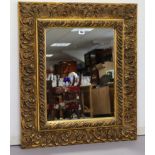 A 19th century-style gilt frame rectangular wall mirror with raised scroll border, 30½” x 26”.