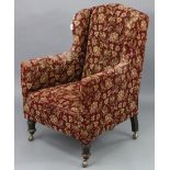 A late 19th century wing-back armchair, upholstered crimson & multi-coloured floral material, & on