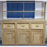 A pine dresser, the upper part fitted two open shelves, the base fitted three frieze drawers above